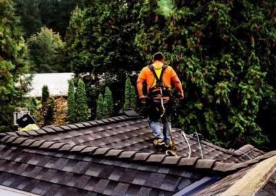A man is standing on top of a roof during a roof installation.