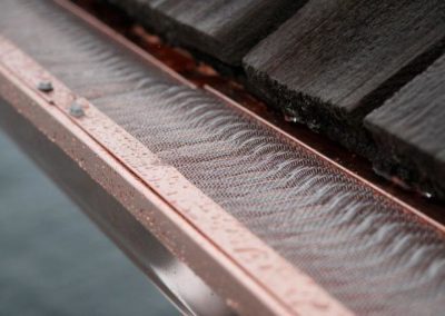 A close up of a copper gutter on a residential roofing.
