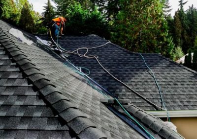 A roofing contractor is working on the roof of a house.