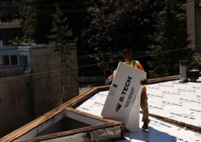 A roofing contractor is laying down shingles on a roof.