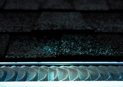 A close up of a gutter with a light shining on it, showcasing the expertise of a residential roofing contractor.