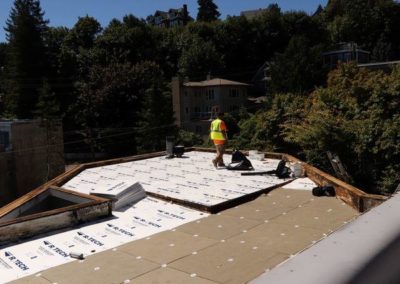 A roofing contractor is working on the roof of a house.