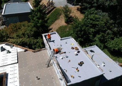 An aerial view of a roof with workers from a roofing company working on it.