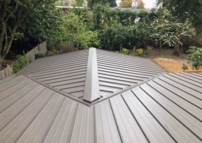 A residential house with a metal roof undergoing roof installation or roof replacement.