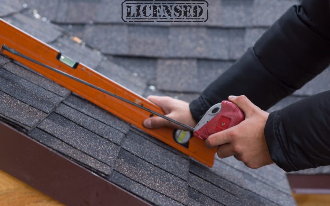 A professional from a roofing company using a tool to measure the shingles on a residential roof for potential replacement.